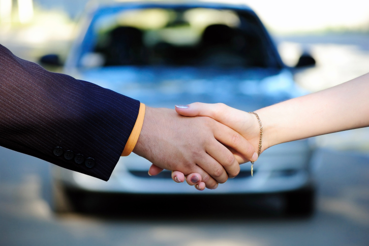 shaking hands in front of car