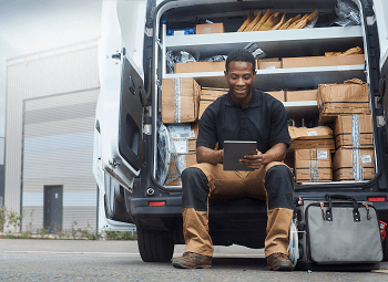 Young man sits in back of commercial van that is filled with packages