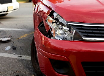 closeup of a red car with a smashed headlight
