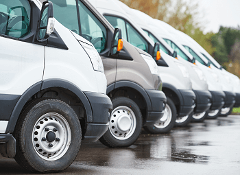 Several commercial vehicles parked in a line in a lot